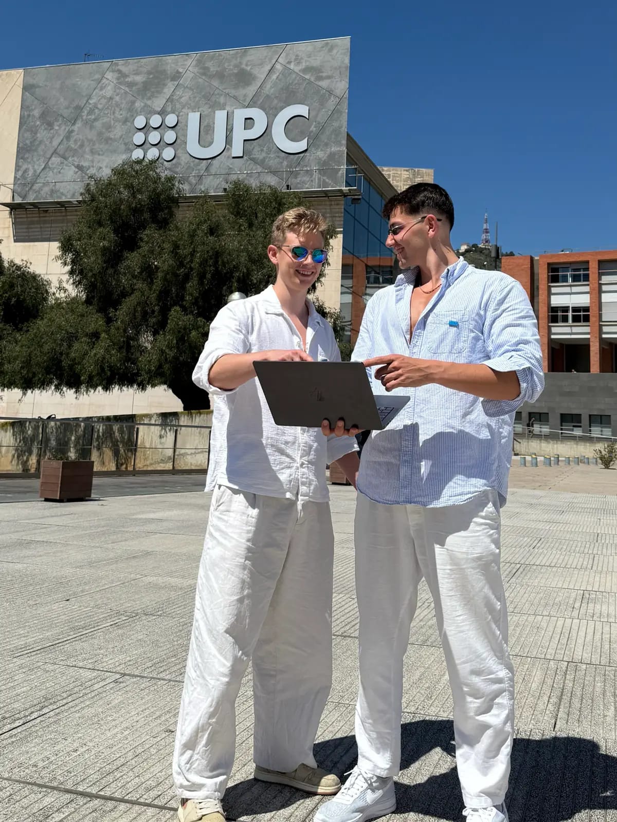 Dvaja ľudia pri otvorenom notebooku pred budovou univerzitného kampusu v Barcelone.