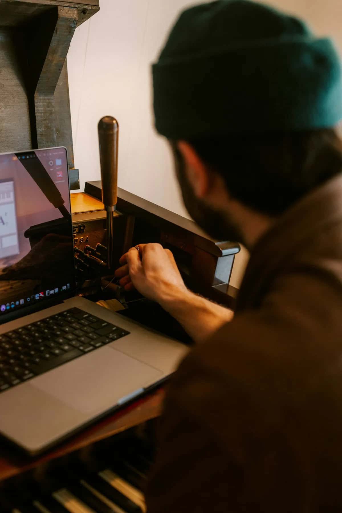 Muž používa notebook pri tradičnom tlačiarenskom stroji