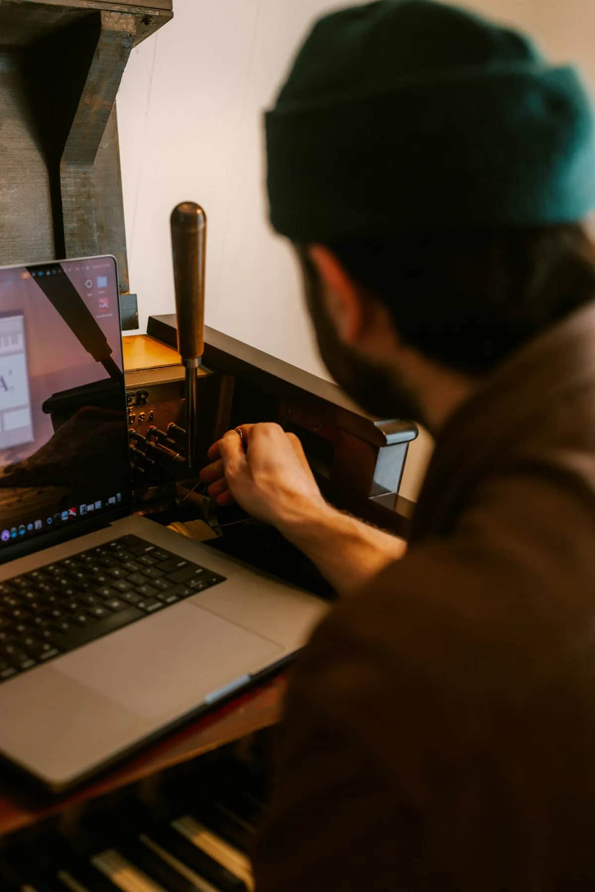 Muž používa notebook pri tradičnom tlačiarenskom stroji